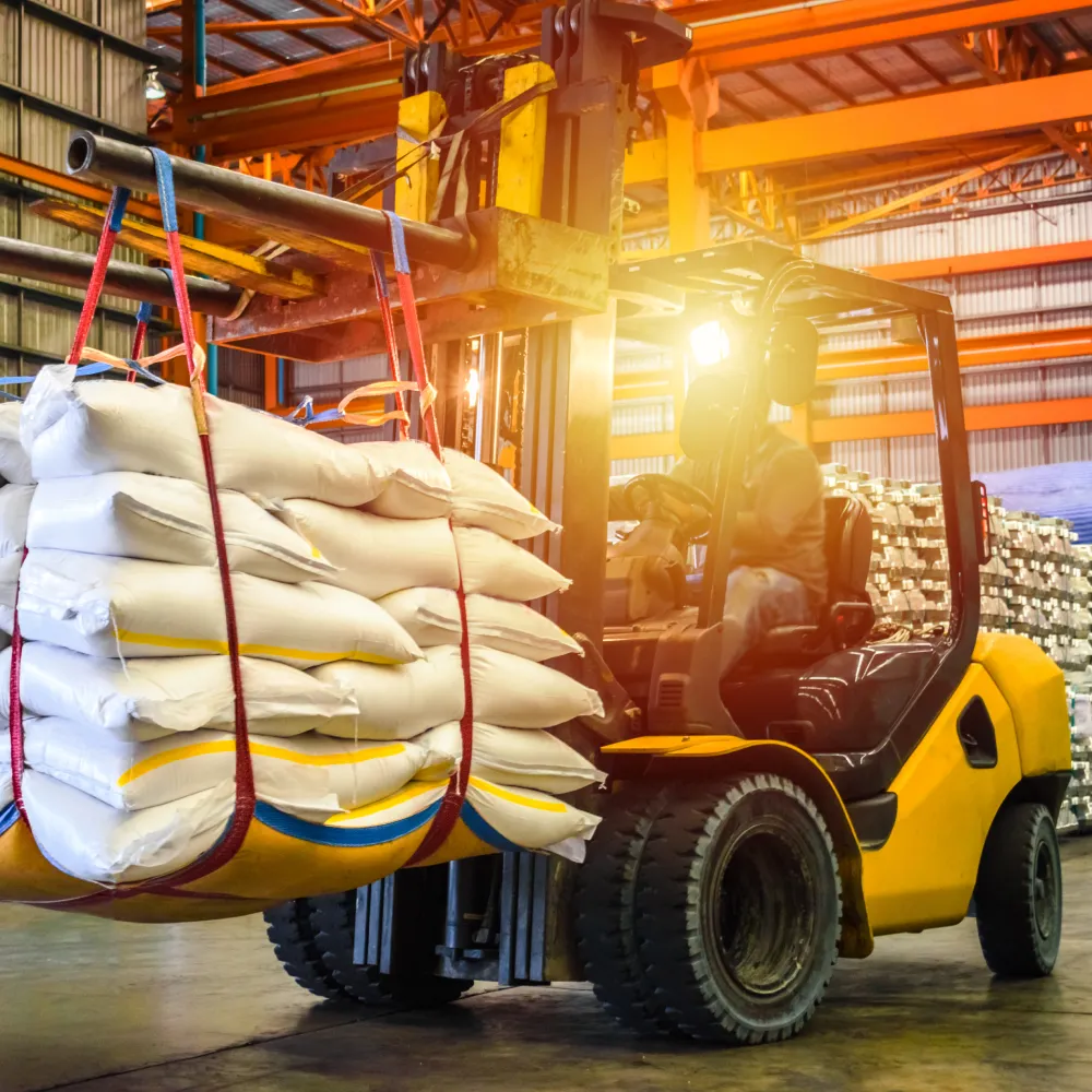 Forklift lifting bags of material in a warehouse setting