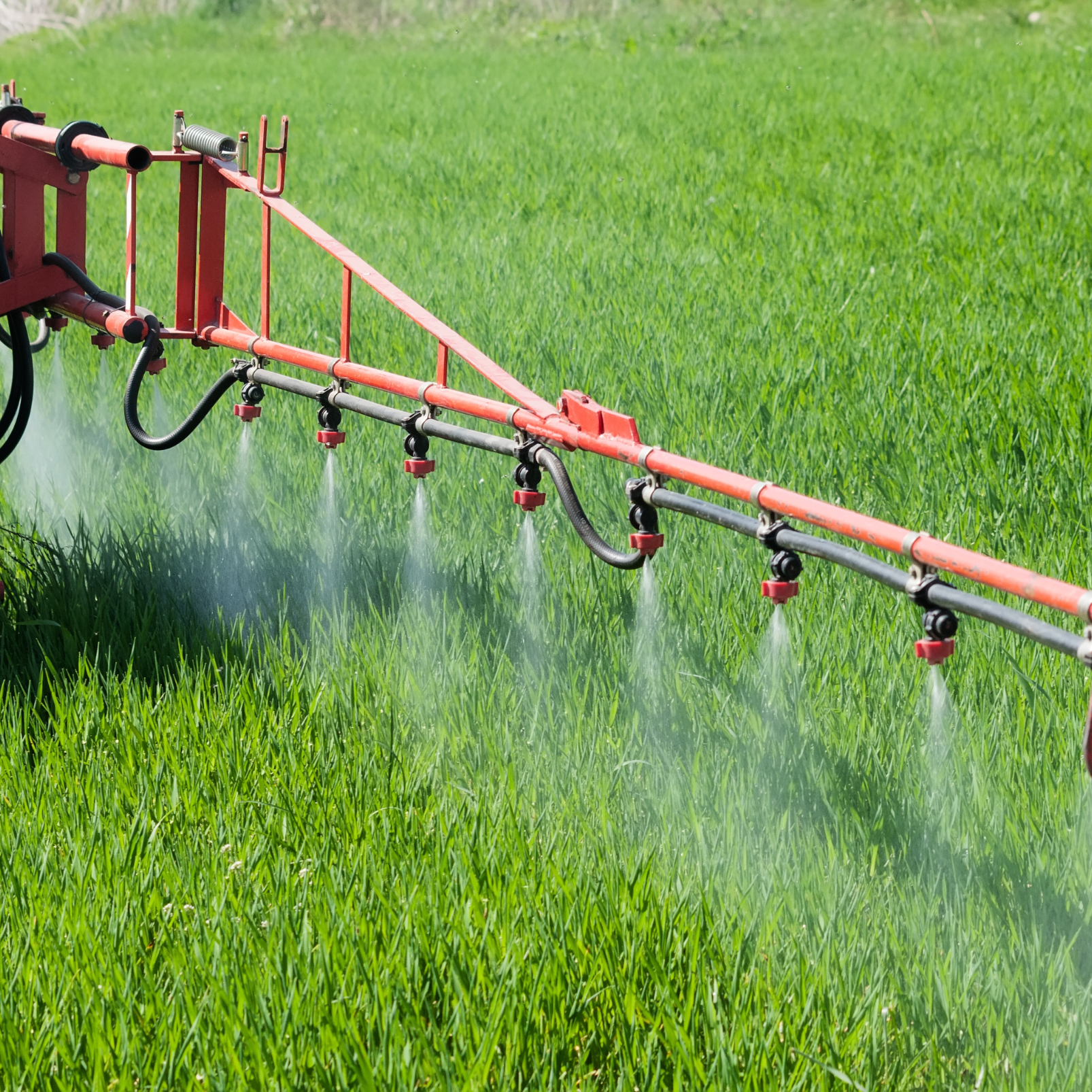 Sprayer applying liquid to lush green grass in a field