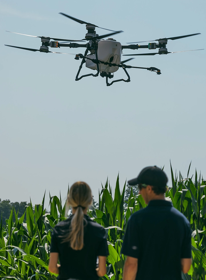 Agricultural drone hovering above two Sylvite agronomists in a corn field