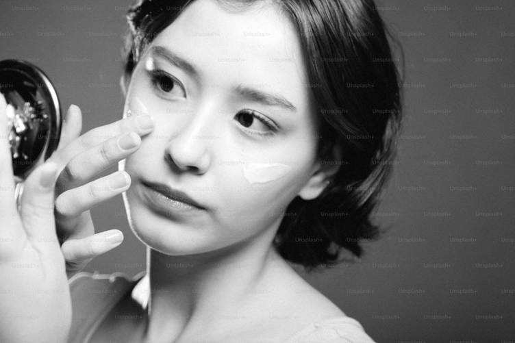 A woman is holding a mirror to her face