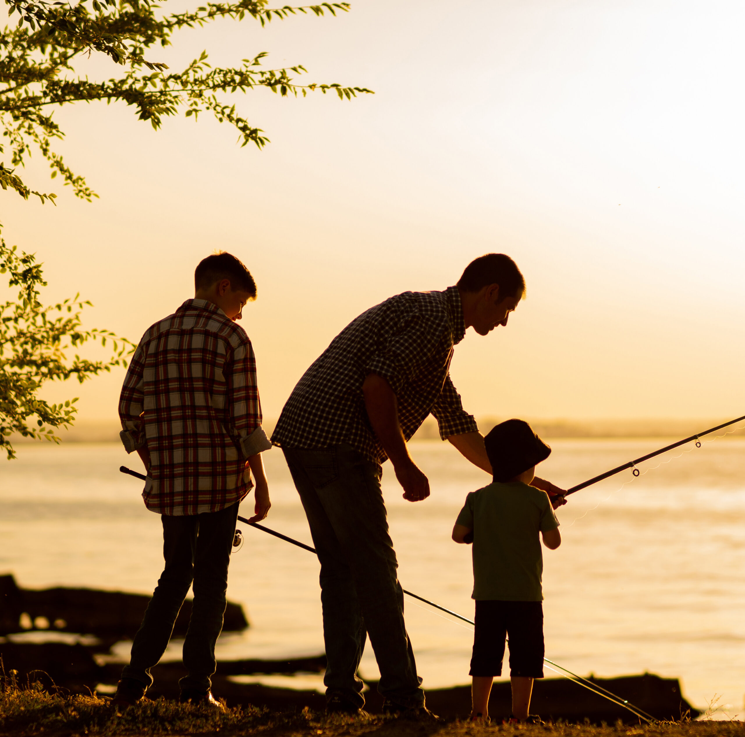 Family dad and two sons are fishing at sunset, silhouette of a man and two boys. ANDRII LYSENKO - STOCK.ADOBE.COM