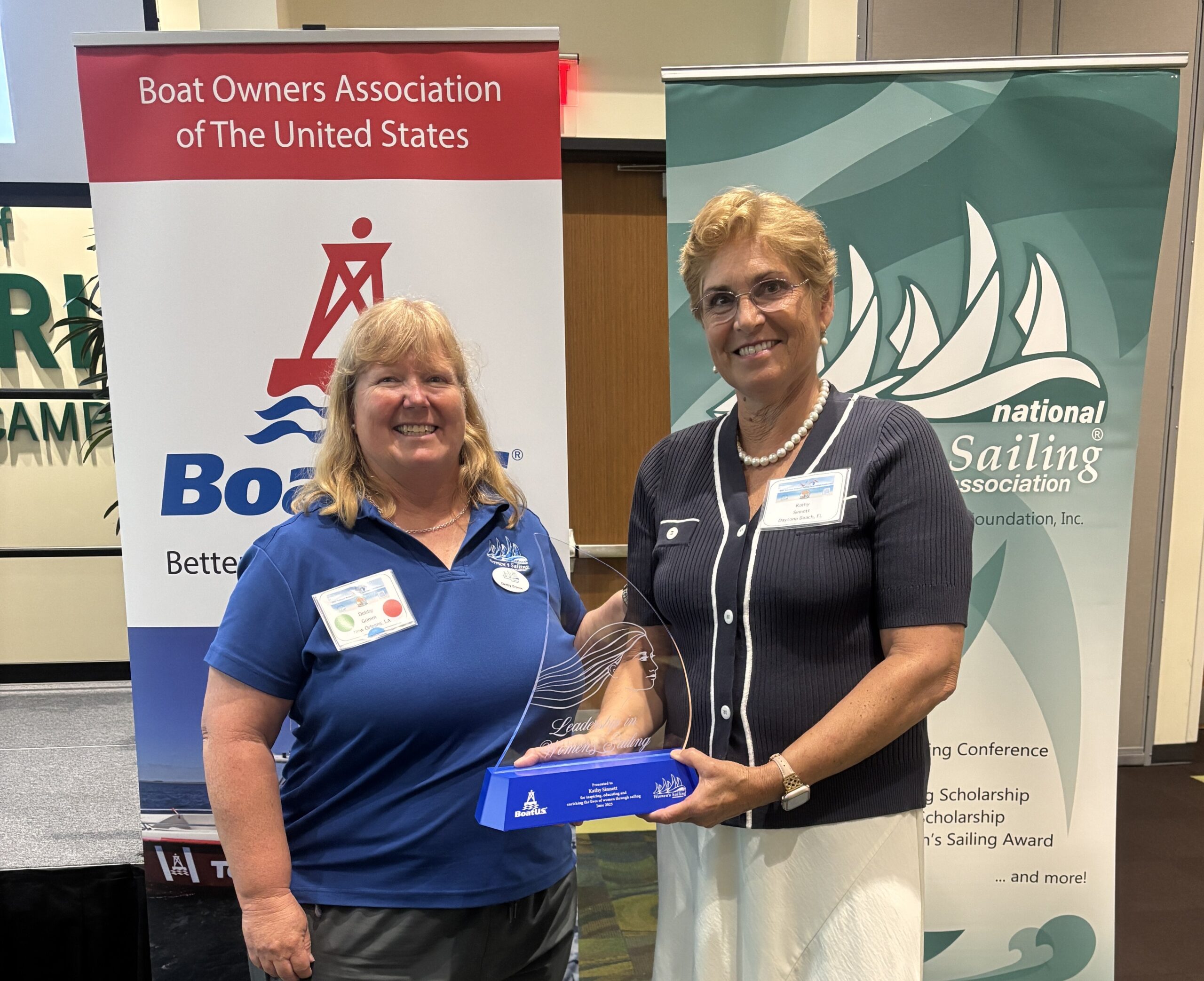 Kathy Sinnett (right) accepts the 2025 BoatUS/NWSA Leadership in Women's Sailing Award from Debby Grimm, president of the National Women's Sailing Association. JAN PEHRSON PHOTO
