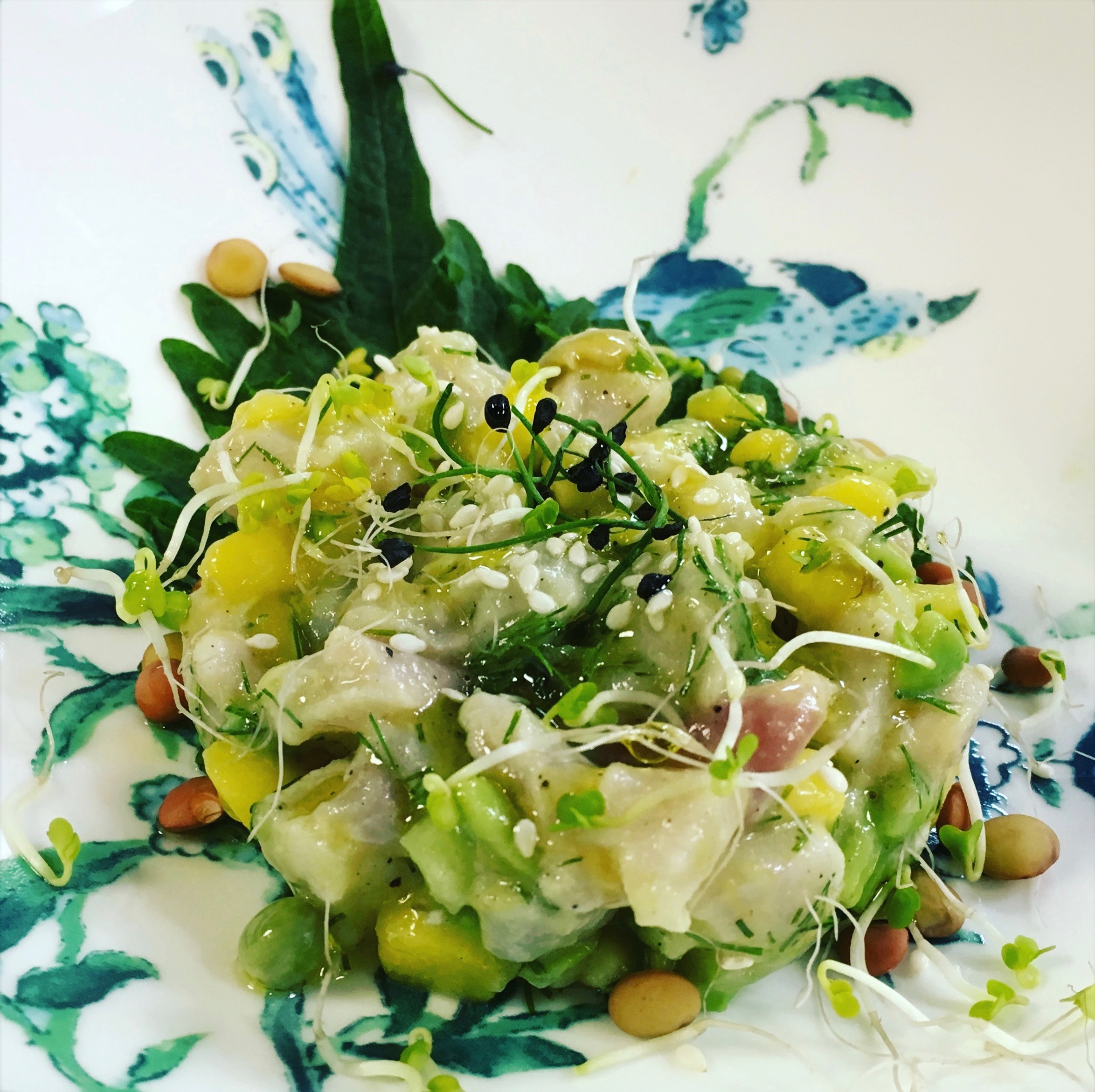 Red snapper ceviche with mango, pineapple, avocado and a light citrus vinaigrette, served on a green shiso leaf and topped with sprouting mixed peas and garlic chive sprouts
