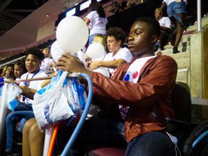 Alto saxophonist and 15-year-old Holland Petway uses a pressurized air spigot to blow up a balloon quickly. After, he’ll tie it by hand. Photo: Phoebe Petrovic/Youth Radio