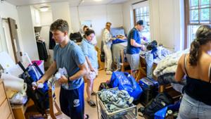 Henry Foster &rsquo;30, far left, unpacks clothes into his dresser while the crowded room of students and parents are busy helping in Dunham Hall