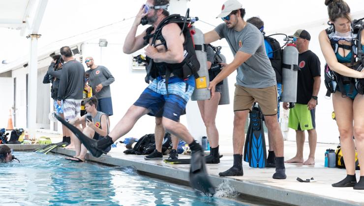Dagger Dive volunteer Preston Perez '22 (center) guides a student into the water.