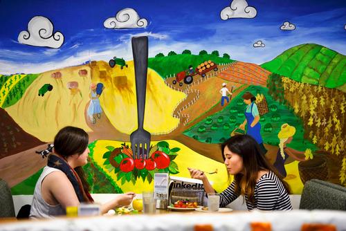 Students eating in McEwen in front of mural