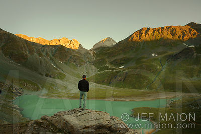 Hiker watching sunrise over lake and mountain landscape