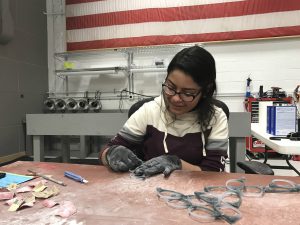 Yunnuen Garcia is scraping and sanding an acetate eyeglass frame in State Optical’s Vernon Hills-based factory.