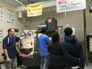 Instructor Jack Krikorian (left) supervises students operating a CNC milling machine at the training facility of the Technology & Manufacturing Association in Schaumburg. Chicago non-profit organization Bethel New Life provides manufacturing skills and supportive career training for community residents at no cost.