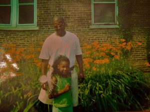 Father stands behind wand-bearing daughter in front of South Shore home.