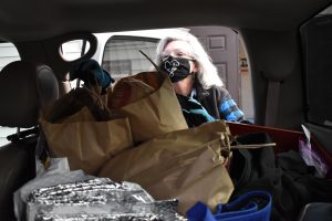 Faith Albano reaches into the back seat of her car to take out bags of bread donations from Hewn and load them into the Hillside Food Pantry.