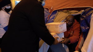 A volunteer gives two care packages to a homeless