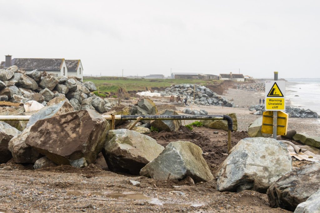 A yellow “Warning Unstable Cliff” sign sits above Bastardstown Beach in Wexford, Ireland. Families that reside near the coastline are at risk of losing their homes due to coastal erosion that is exacerbated by sea level rise. (Cathy Ching / Medill)