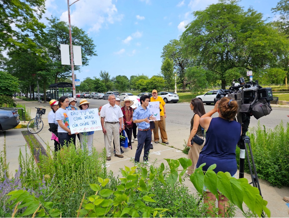 Vietnamese Americans hold signs as state Rep. Hoan Huynh talks to a reporter.