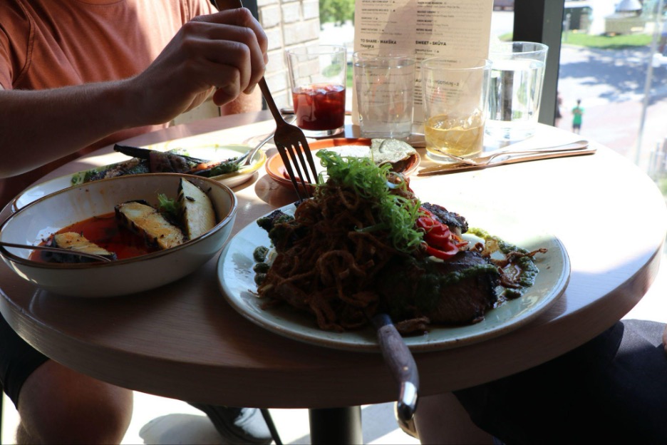 Bison ribeye on plate surrounded by other dishes