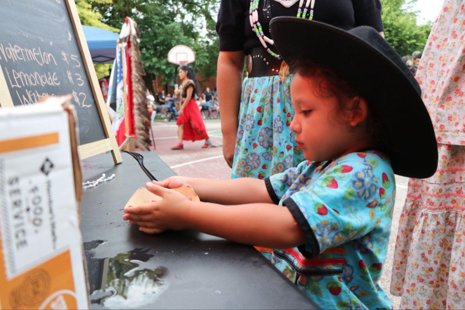 Child in hat at Native food stand