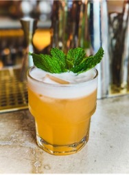 Singani cocktail with foamy top and leafy garnish