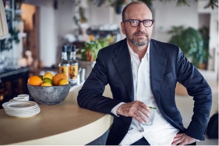 Man in suit sits at bar while holding cocktail glass