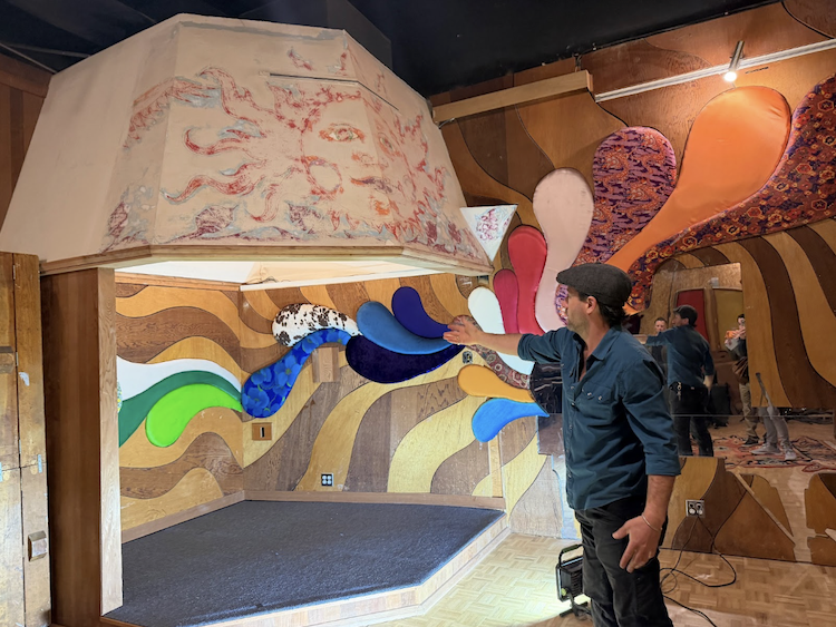 Man in Sausalito's 2200 Studios with colorful wall art.