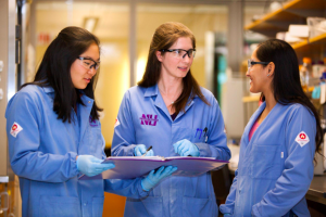 Researchers in lab coats discuss notes