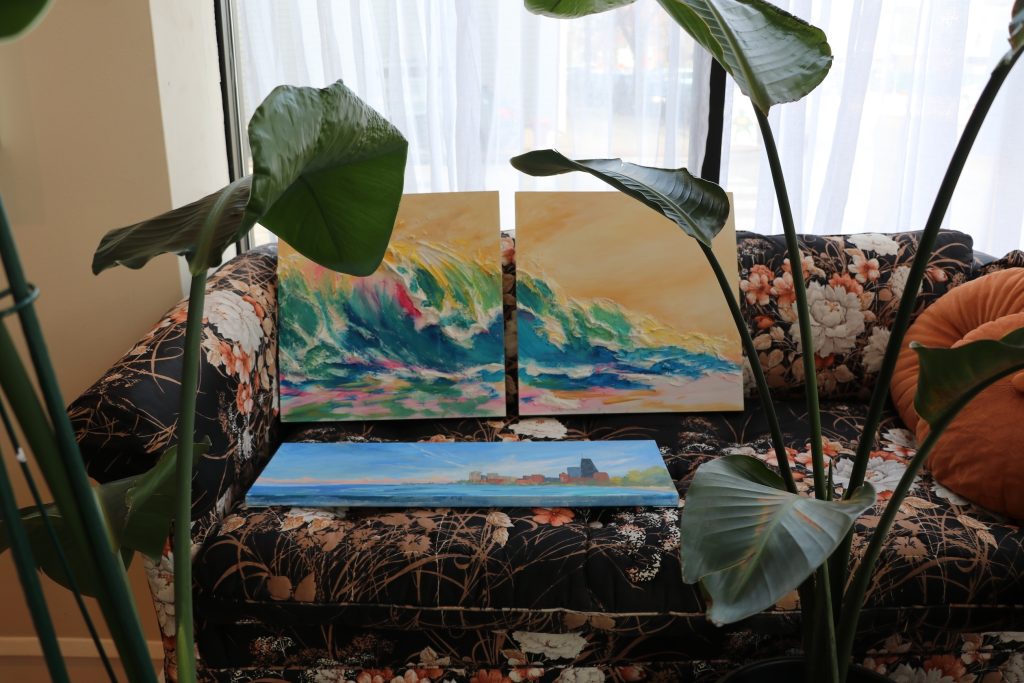 Paintings of waves and a cityscape on a floral couch