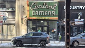 A car is parked in front of the Central Camera store.