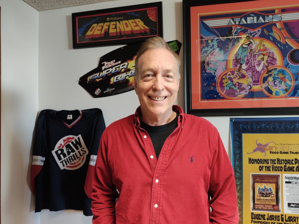 Jarvis smiling, surrounded by vintage arcade game posters.