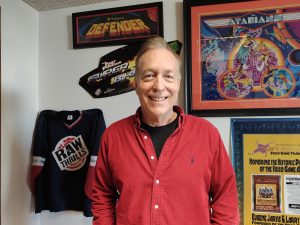 Jarvis smiling, surrounded by vintage arcade game posters.