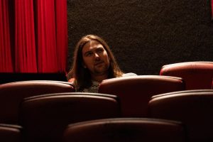Peter Kuli in the Davis Theater with a red curtain behind him.