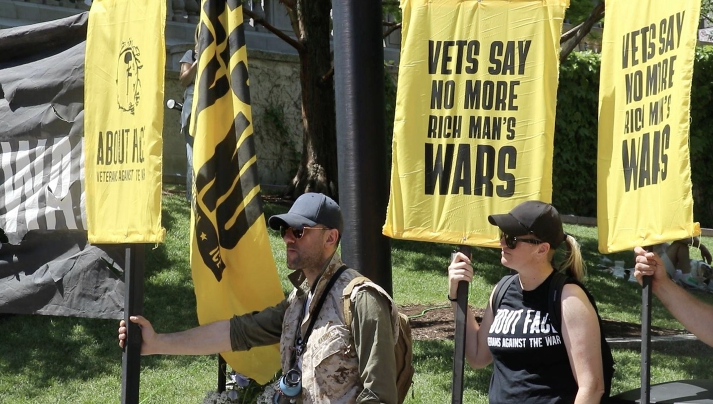 Protestors hold signs: "Vets Say No More Rich Man's Wars