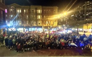 Large group of people at night in front of buildings.