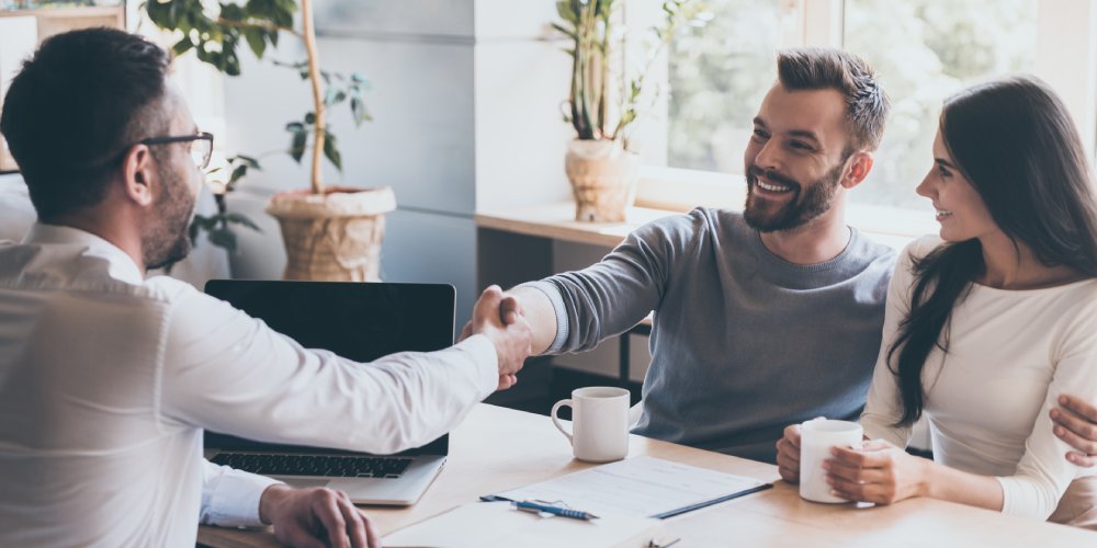 Couple shaking hands with sells manager.