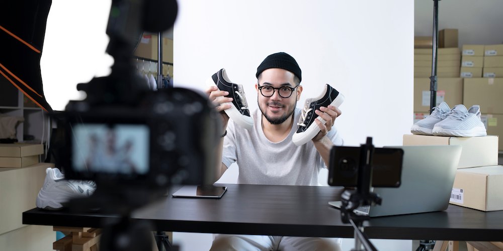Young asian man doing a sneaker review while recording himself