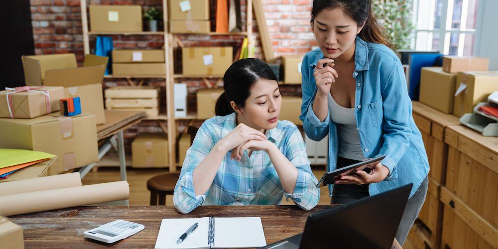 2 Young asian women looking at a tablet with customer orders