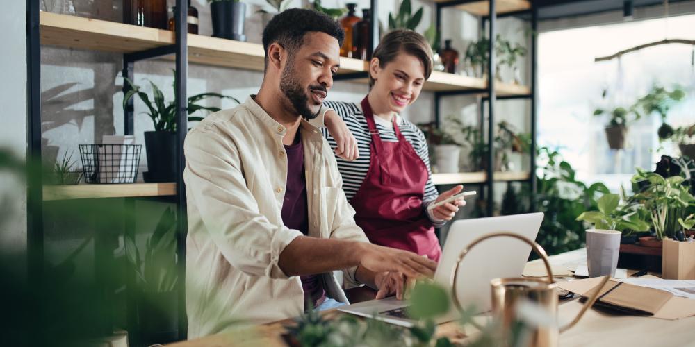 Two diverse business owners standing together at a table in their flower shop