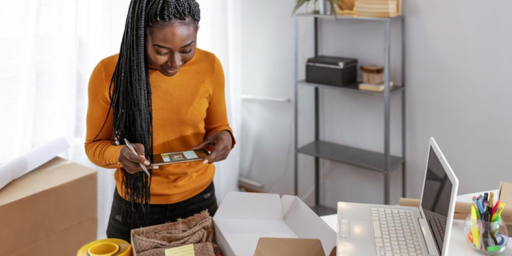 Launch or Grow Your E-Commerce Business Black female business woman working from home setting up orders to send out.