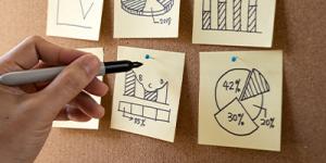 Person drawing graphs Person drawing different graphs on post it notes that are on a cork board