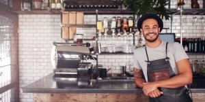 Black, male small business owner stands in his coffee shop