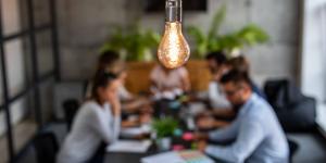 Business team gathered at table with a lightbulb hovered over Business team gathered at table with a lightbulb hovered over