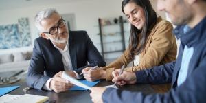 Attractive couple signing contract with real-estate agent in contemporary house