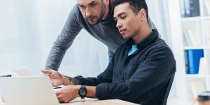 serious male coworkers working with papers and laptop in office