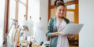 Young woman tailor with laptop is answering emails