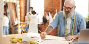 Celebrate, Reflect, Plan Senior tailor or fashion designer making sketch of new items for seasonal collection by workplace