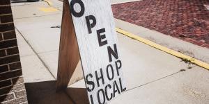 "open, shop local" sandwich board sign positioned on sidewalk