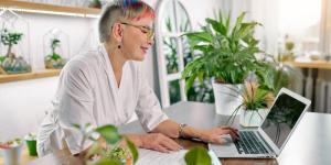 Beautiful florist have short colorful hairstyle, look at screen of laptop.