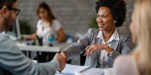 African american woman advisor shaking hands with clients in the office.