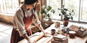 Young woman making pottery at creative studio standing rolling clay joyful in daylight Young woman making pottery at creative studio standing rolling clay joyful in daylight