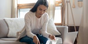 Focused young caucasian woman sit on couch at home manage family household finances