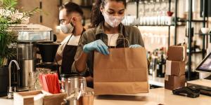 Two baristas wearing medical mask serving coffee